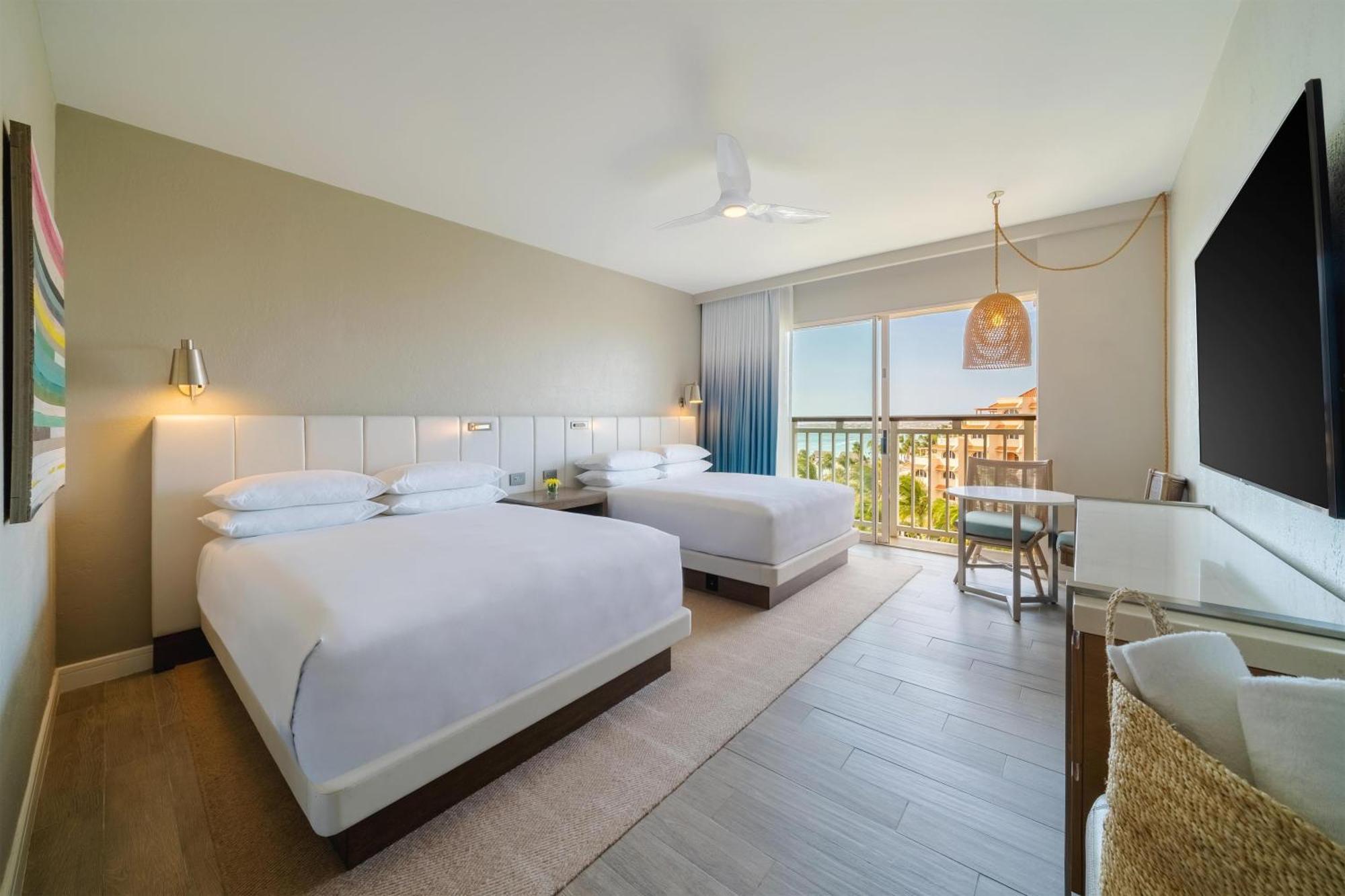 Zimmer mit 2 Queensize-Betten sowie Blick auf das Resort und das Meer
